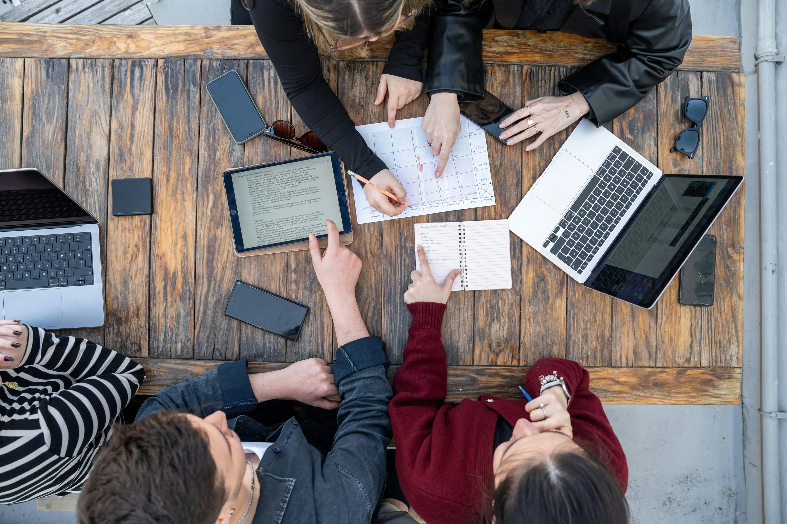 A team collaborating on a global strategy with maps, tablets, and laptops, symbolizing the active community at Global Play Network.