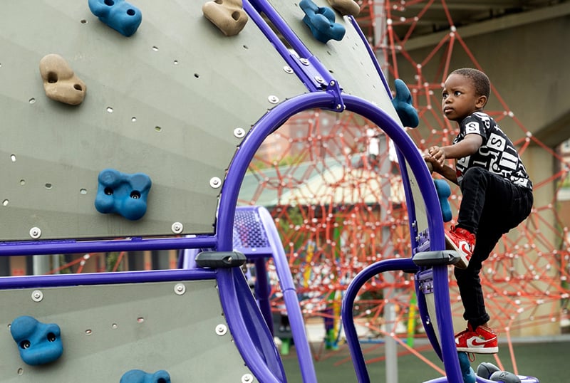 young-black-boy-climibing-playground-device-Playcore-Photo